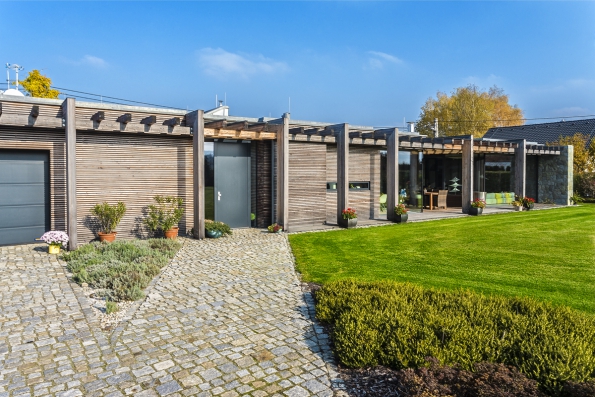 Bezbariérový přízemní dům lemuje podél celé jižní fasády pergola z lepených dřevěných hranolů. Stavba je z obou stran „sevřena“ masou kamenných zdí. Terasa ležící v rovině trávníku dává spolu s plně prosklenou fasádou s bezrámovým zasklením pocit, že interiér přímo přechází do zahrady a naopak. Bezbariérový přízemní dům lemuje podél celé jižní fasády pergola z lepených dřevěných hranolů. Stavba je z obou stran „sevřena“ masou kamenných zdí. Terasa ležící v rovině trávníku dává spolu s plně prosklenou fasádou s bezrámovým zasklením pocit, že interiér přímo přechází do zahrady a naopak.